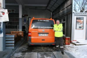 Der Kfz-Sachverständige steht professionell vor seinem Firmenfahrzeug.