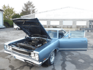 Ein geöffneter Oldtimer-Motorraum wird von einem Kfz-Gutachter analysiert.