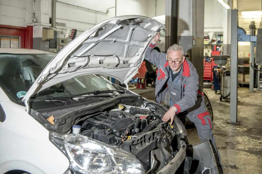 Der Kfz-Gutachter prüft den stark beschädigten Motor eines Unfallfahrzeugs und analysiert den Schaden für ein professionelles Gutachten.