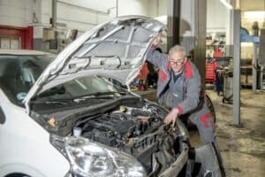 Der Kfz-Gutachter prüft den stark beschädigten Motor eines Unfallfahrzeugs und analysiert den Schaden für ein professionelles Gutachten.