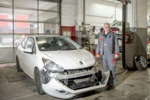 Der Kfz-Sachverständige steht in seiner Werkstatt und überprüft ein Fahrzeug für ein professionelles Gutachten.