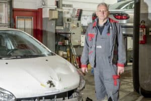 Der Kfz-Gutachter steht in seiner Werkstatt, um Fahrzeuggutachten und Schadensbewertungen durchzuführen.