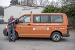 Der Kfz-Gutachter steht professionell vor seinem Firmenwagen, bereit für den nächsten Einsatz zur Begutachtung von Fahrzeugschäden.