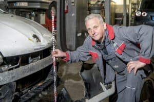 Ein Kfz-Gutachter misst präzise einen Schaden am Fahrzeug zur genauen Begutachtung und Dokumentation.