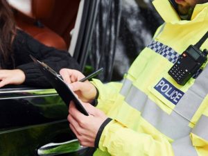 Polizeibeamter notiert Angaben bei einem Verkehrsunfall im Auto als Grundlage für die Unfallaufnahme