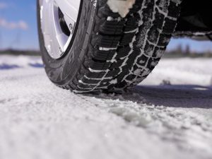 Nahaufnahme eines Winterreifens auf Schnee als Symbol für Glätte und erhöhtes Unfallrisiko im Winter