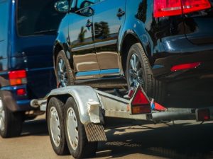 Auto auf einem Transportanhänger im Straßenverkehr als Motiv für Unfall mit Anhänger und Unfallgutachten