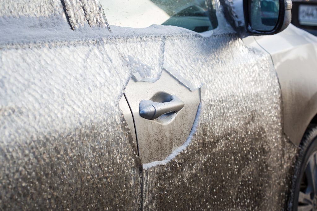 Eingefrorenes Auto im Winter. Vereiste Autotür mit Eis als Symbol für Winterwetter eingeschränkte Sicht und erhöhtes Unfallrisiko.