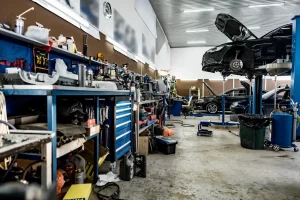 Eine weitläufige und belebte KFZ Werkstatt in Oberhausen mit mehreren Fahrzeugen auf Hebebühnen und einer großen Werkbank voller Spezialwerkzeuge für die technische Begutachtung.