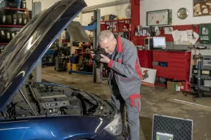 Kfz Gutachter in Herten bei der fotografischen Dokumentation und Schadensbewertung an einem BMW Motorraum in einer Werkstatt