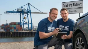 Zwei freundliche KFZ Sachverständige in grünen Poloshirts und Warnwesten dokumentieren einen Unfallschaden an einem Fahrzeug im Duisburger Hafen. Im Hintergrund ist ein großer Hafenkran sowie ein Ortsschild von Duisburg Ruhrort zu sehen.
